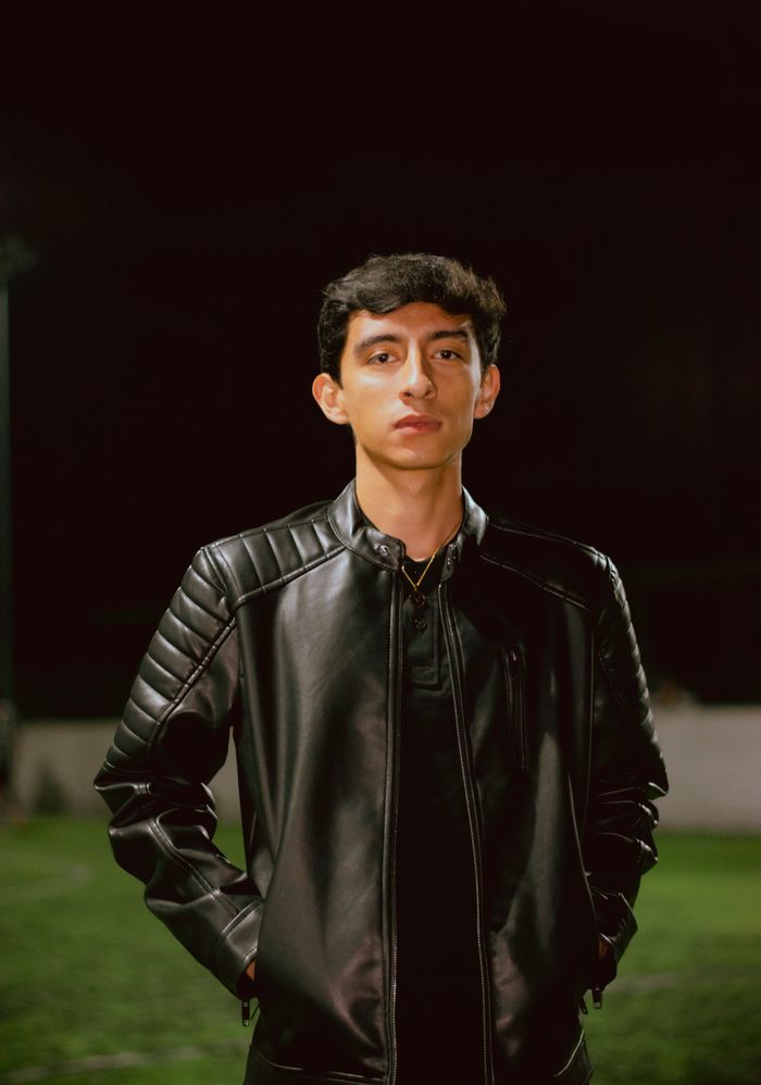 gallery-01 A young adult wearing a black leather jacket standing outdoors at night.