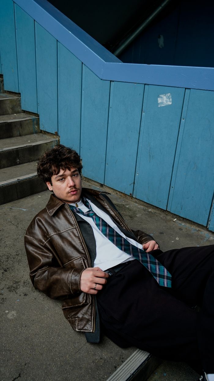 why-choose-us-01 Young man in leather jacket relaxing on stairway steps in an urban setting.